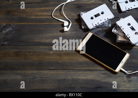 Smartphones und Kassetten auf Holz- Hintergrund. Moderne und retro Technologien Hintergrund Konzept. Ansicht von oben mit der Kopie. Stockfoto