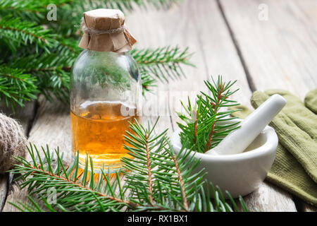 Tanne aromatische Öl. Kiefer ätherisches Öl in einer Glasflasche. Nadelholz Äste, Handschuhe und Mörtel. Stockfoto