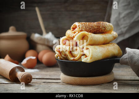 Bratpfanne von frisch gebackenen Pfannkuchen, Zutaten und Küchenutensilien für Pfannkuchen. Stockfoto