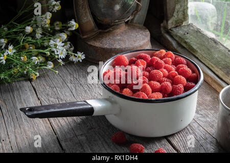 Schüssel voller Himbeere Beeren auf hölzernen Tisch in einer retro Haus im Dorf. Stockfoto