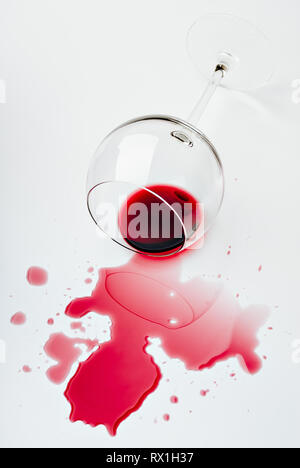 Rotwein verschüttet aus einem Weinglas auf eine weiße Fläche Stockfoto