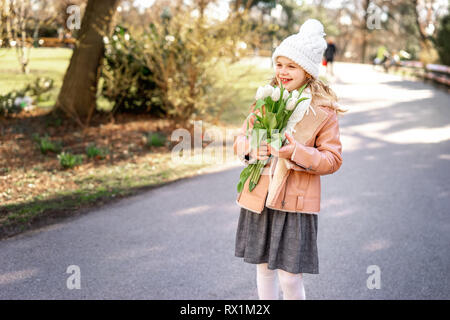 Kleines Mädchen Wanderungen im Frühling im Garten mit Blumenstrauß aus Tulpen Stockfoto