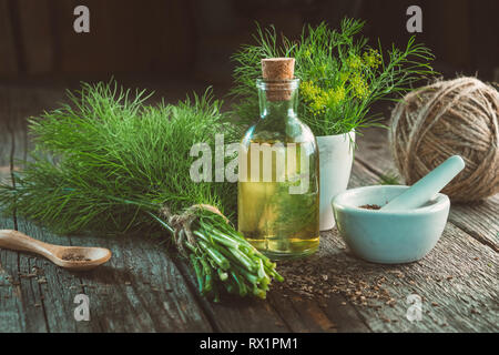 Bündel frischer grüner Dill, Mörtel von Fenchel Samen, Flasche dill Öl- und Jute auf Holzbrett. Stockfoto