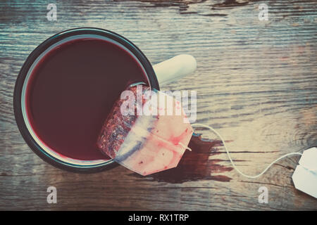 Teebeutel von roten Früchten und Beeren, Tee in der Zubereitung von Tee in emaillierten Becher. Stockfoto