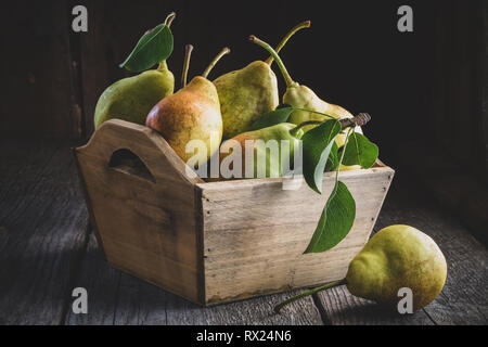 Frische reife Birnen in einer Holzkiste auf hölzernen Tisch. Stockfoto