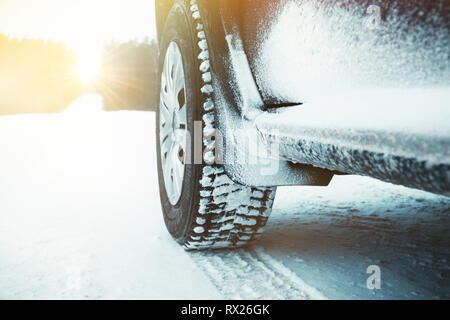 Pkw-Reifen Winter mit Schnee auf der Straße durch den Wald am sonnigen Tag abgedeckt. Stockfoto
