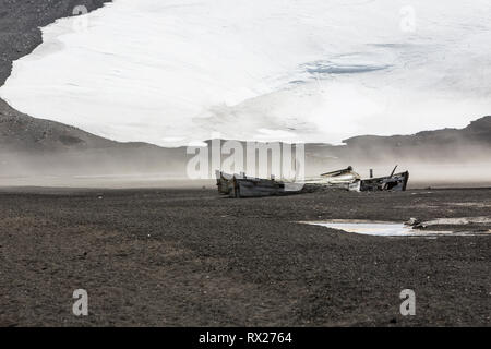 Relikte der Vergangenheit, einschließlich dieser Wasserboote, die in der Walfangindustrie verwendet wurden, liegen über den Strand von Whaler's Bay auf Deception Island, South Shetland Islands, Antarktis verstreut. Stockfoto