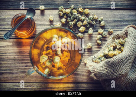 Gesunde Kamille Tee Tasse, hessische Beutel der trockenen Daisy Blumen und Honig jar. Ansicht von oben. Stockfoto