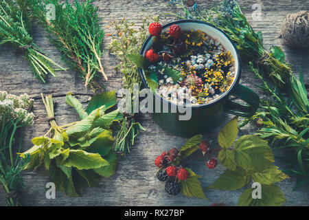 Gesunde Kräuter Tee aus emailliertem Tasse und Trauben von heilenden Kräutern. Die Kräutermedizin. Retro getönt. Stockfoto