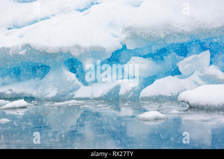 Eine geerdete Eisberg wird langsam in Schnee von einem Sommer Sturm in der Nähe von pleneau Pleneau Insel, Insel, Lemaire Kanal, Antarktische Halbinsel abgedeckt Stockfoto