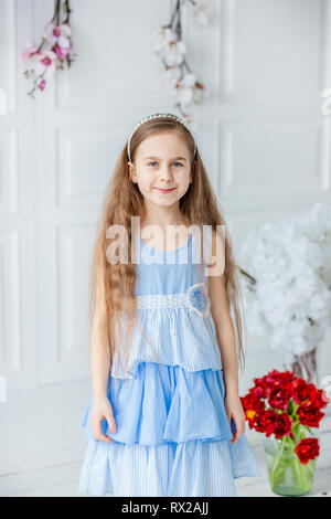 Porträt einer wunderschönen blau-Eyed Girl, ein kleines Mädchen unter den Frühling Blumen in einem hellen Raum. Spring Break, Muttertag, Frauentag, Ostern. Stockfoto