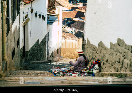 Eine indigene Frau auf dem Boden den Verkauf handwerklicher Produkte auf die alten gepflasterten Straßen von Cusco, Peru sitzen. Stockfoto