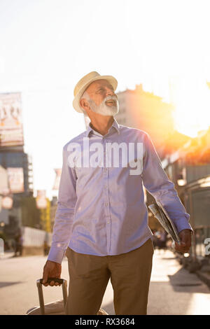 Happy Senior touristische Mann mit Koffer in die Stadt. Stockfoto