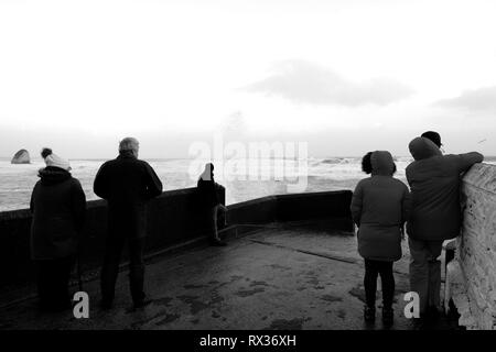 Eine Gruppe von Menschen beobachten das Wetter und die Wellen an der Freshwater Bay auf der Isle of Wight, Großbritannien. Stockfoto