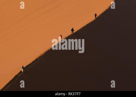 Touristen einen großen roten Sanddünen in Sossusvlei, Namibia klettern. Stockfoto