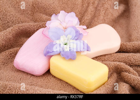 Bunte Seifen und Blumen auf braun Handtuch. Stockfoto