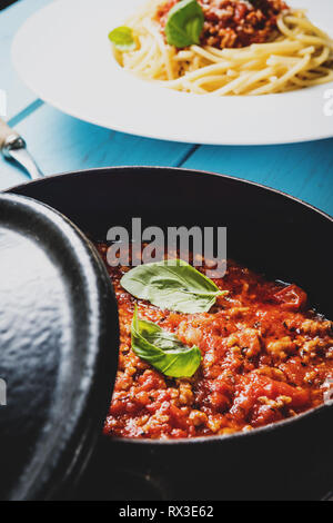 Traditionelle italienische Pasta Spaghetti Bolognese mit Hackfleisch, Tomaten, Käse Parmesan und Basilikum auf Blau Holz Tisch Stockfoto