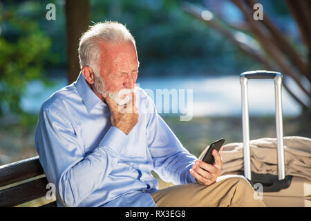 Bärtige ältere Menschen schreiben Nachricht in den Park. Stockfoto