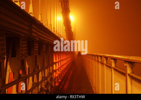 Geisterhafte Abbildung auf der Menai Suspension Bridge, während der Nebel und Nebel Stockfoto