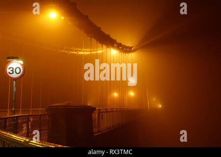 Misty und Neblig Menai Suspension Bridge in der Nacht. Diese Brücke verbindet die Waliser Festland mit der schönen Insel Anglesey. Stockfoto