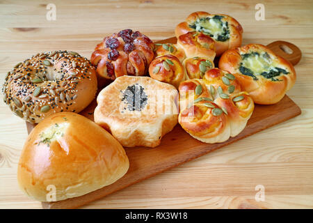 Verschiedene Brötchen und Gebäck auf einem Tablett serviert auf hölzernen Tisch Stockfoto