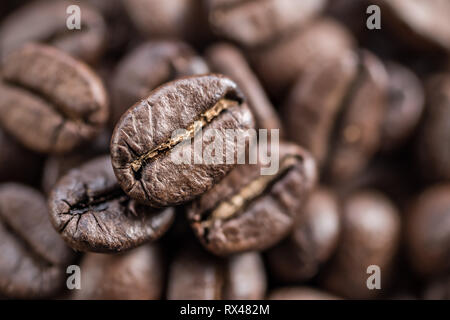 Drei geröstete Kaffeebohnen hautnah. Verschwommen Kaffeebohne Hintergrund. Ansicht von oben. Stockfoto