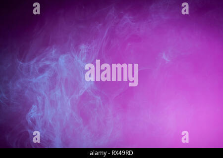 Nebel gefärbt mit hellen blauen Gel auf dunklem Rosa Hintergrund Stockfoto