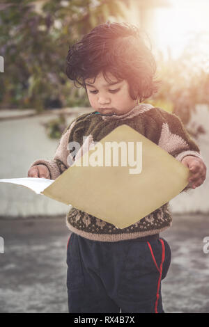 Portrait von Cute 2 Jahr wenig Asiatischen baby girl Holding und in Bild Buch suchen Stockfoto