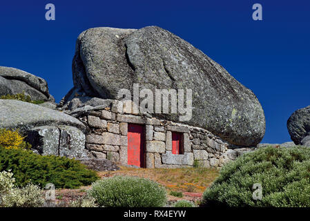 Granit Stein Haus in riesigen Felsen mit dunkelblauen Himmel an einem sonnigen Tag integriert Stockfoto