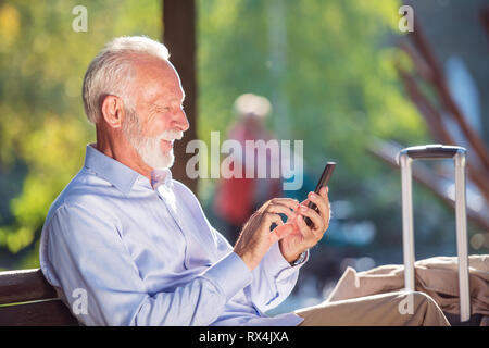 Bärtige ältere Menschen schreiben Nachricht in den Park. Stockfoto