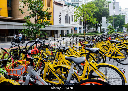 Gelben Ofo Leihfahrräder Teil von Singapurs erfolglosen Bike. das Programm wurde Bencoolen St Singapur mit Person reiten Motorrad im Hintergrund geparkt Stockfoto