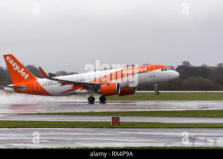 EasyJet Airbus fliegt auf der nassen Landebahn am Flughafen Manchester ab. Stockfoto