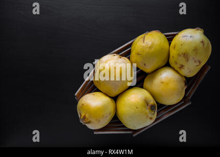 Quitten in Holz- korb auf schwarzem Hintergrund Stockfoto