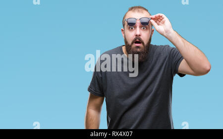 Junge kaukasier hipster Mann mit Sonnenbrille über isolierte Hintergrund Angst und mit Erstaunen Ausdruck, Angst und aufgeregt Gesicht schockiert. Stockfoto