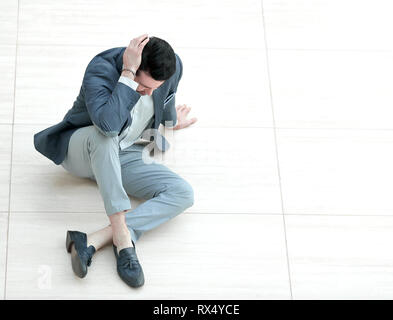 Frustrierte junge Unternehmer sitzen auf dem Boden und blickte nach unten. Stockfoto