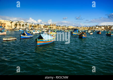 Alten bunten Boote im Hafen von Marsaxlokk Luzzu am sonnigen Tag. Blauer Himmel mit Wolken Stockfoto