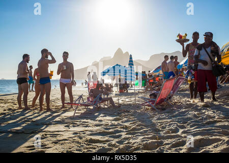 RIO DE JANEIRO - Februar 5, 2017: Unlicensed Strand verkäufer, Bier und hausgemachten Caipirinha cocktails Spaziergang am Strand von Ipanema auf der Suche nach Kunden Stockfoto