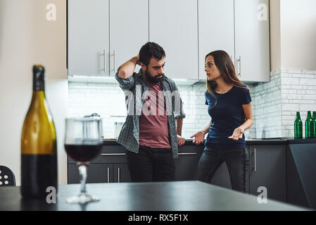 Portrait von Mann und Frau in Argument, in der Küche stehen. Eine Flasche und ein Glas Wein auf dem Tisch. Selektiver Fokus Stockfoto