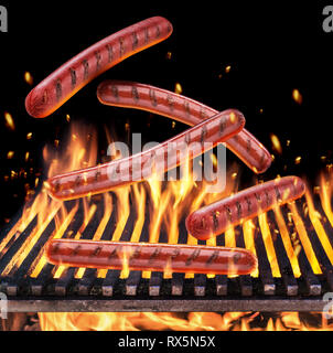 Würstchen fallen auf den brennenden Grill Gitter und Zungen wie von Feuer Flamme. Stockfoto