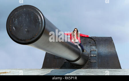 Bateria de Castillitos, Spanien - 28. Februar - 2019: Frau possing an der Spitze eines beeindruckenden militärischen Cannon für Küstenschutz Stockfoto