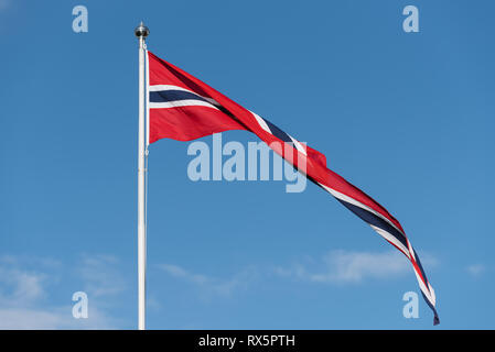 Norwegische Flagge auf einem Fahnenmast vor blauem Himmel. Sonniges Wetter in Norwegen Stockfoto