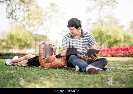 Asiatische Paare, ein Buch zu lesen. Paar Studenten mit einem Bücher. Bildung in der Natur Park Stockfoto