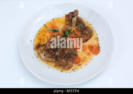Fried Chicken leg mit Tomaten und Gewürzen auf einer Platte Stockfoto