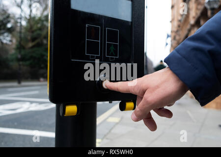 Nahaufnahme von einem kaukasischen Mann treibt ein fussgänger Call Button in einem Zebrastreifen in London, Vereinigtes Königreich Stockfoto