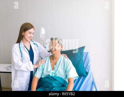 Schöne asiatische Arzt darauf achten, dass der Patient im Krankenhaus bed Stockfoto