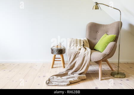 Eine Lesung Stuhl / Sessel mit einer Lampe, Decke und ein offenes Buch. Leere weiße Wand im Wohnzimmer. Platz kopieren Stockfoto