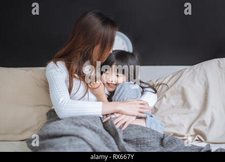 Glückliche Mutter und ihre Tochter Mädchen spielen und schmusen im Schlafzimmer Stockfoto