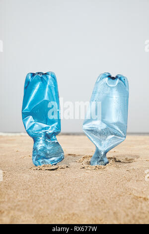 Zwei Plastikflaschen in Sand stecken an einem Strand, selektiver Fokus, Farbe Tonen angewendet. Stockfoto