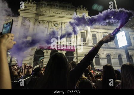 Eine Frau gesehen, die eine lila Farbe Flair in der Luft während des Tages März den Internationalen Frauentag. Tausende Menschen versammelten sich auf den Straßen von Montevideo gegen Gewalt gegen Frauen und die Gleichstellung von Männern und Frauen zu verlangen. Stockfoto