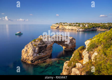 Es Pontas in Mallorca, Natural Arch im Mittelmeer bei Sonnenaufgang mit einem Schiff vor Anker in der Nähe der Ferienwohnungen und Apartments im backgroun Stockfoto